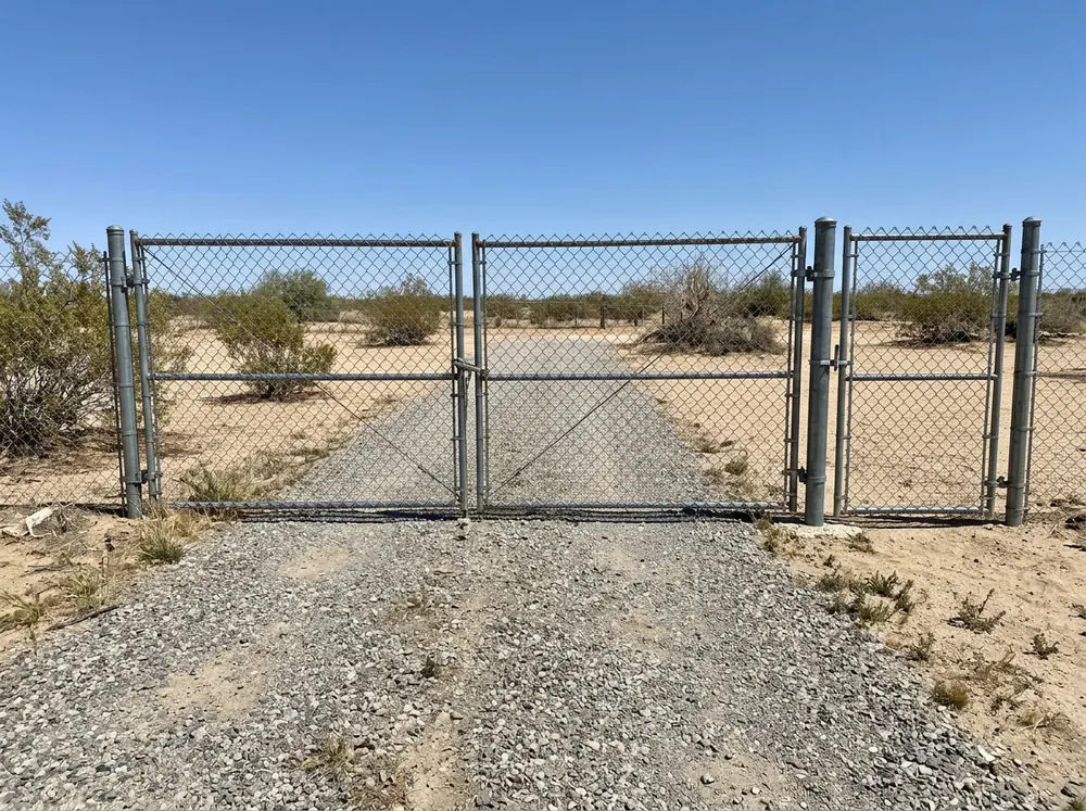 A galvanized chain link double drive gate beside a single walk gate