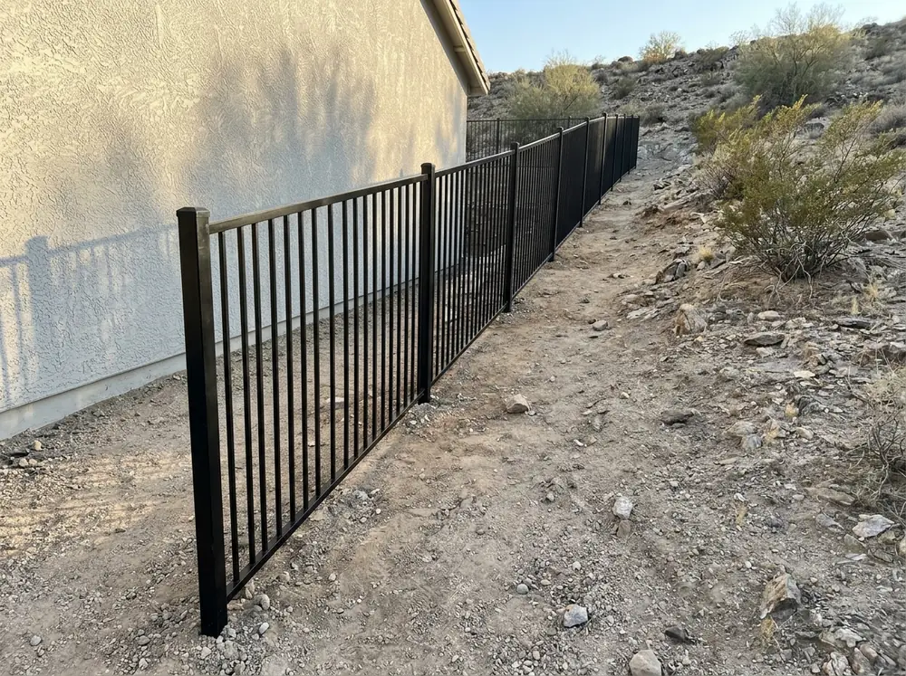 Black aluminum fence panels angled to follow a sloped side yard with no gap under the bottom rail